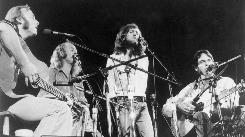 Stephen Stills, David Crosby, Graham Nash, and Neil Young performing onstage with guitars