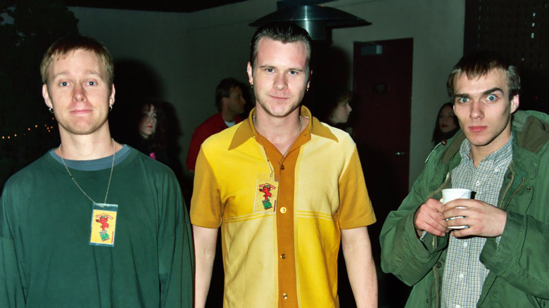 Three members of sunny day real estate standing and smiling at event
