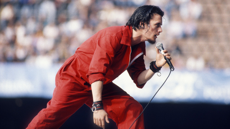 Mike Patton singing in red jump suit on stage