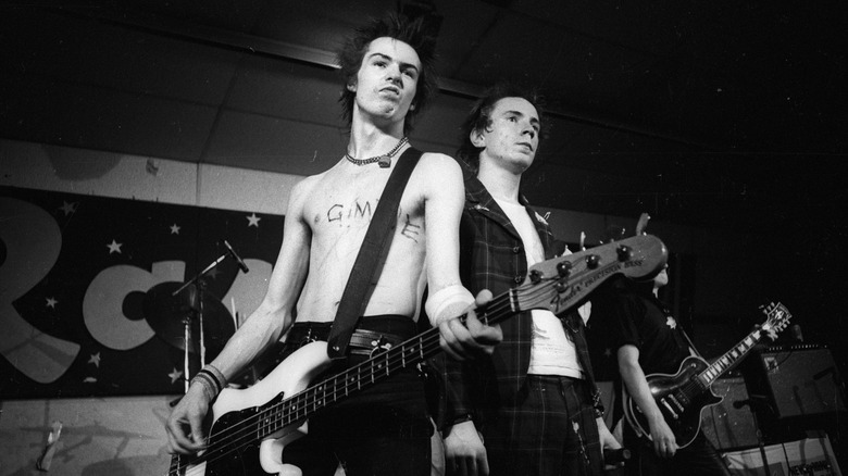 Sid Vicious with Johnny Rotten on stage holding guitar