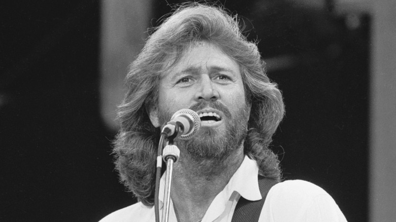 Barry Gibb singing onstage and looking into crowd