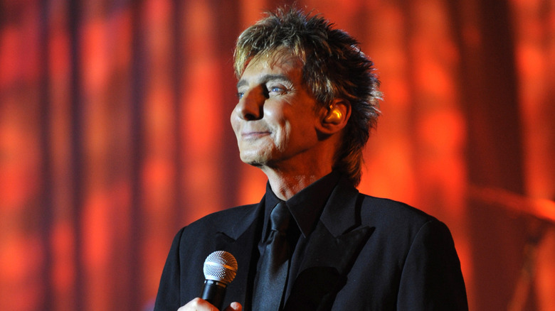 Barry Manilow in dark suit with red background performing in 2009