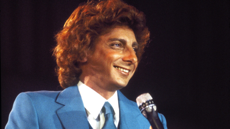 Barry Manilow holding a microphone while wearing a blue suit
