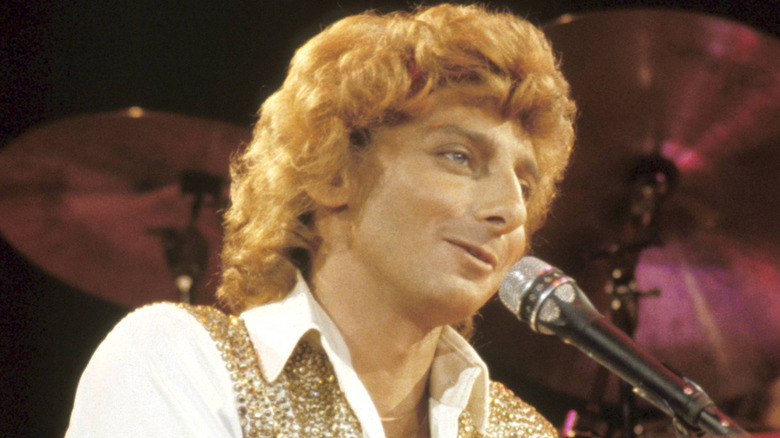 Barry Manilow smiling at piano on stage