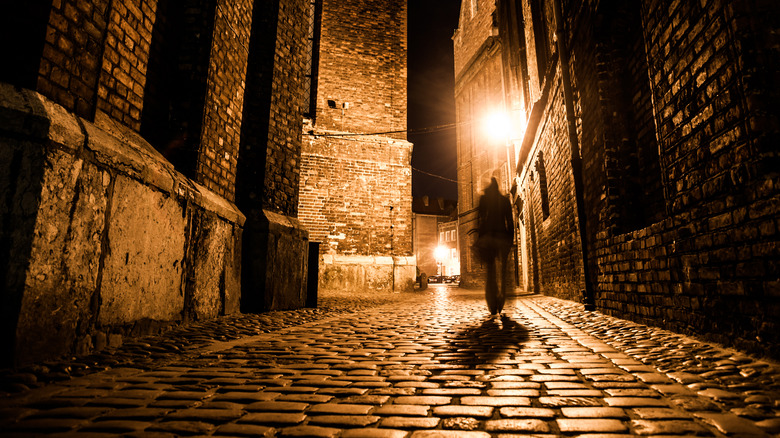 silhouette of man walking in alley
