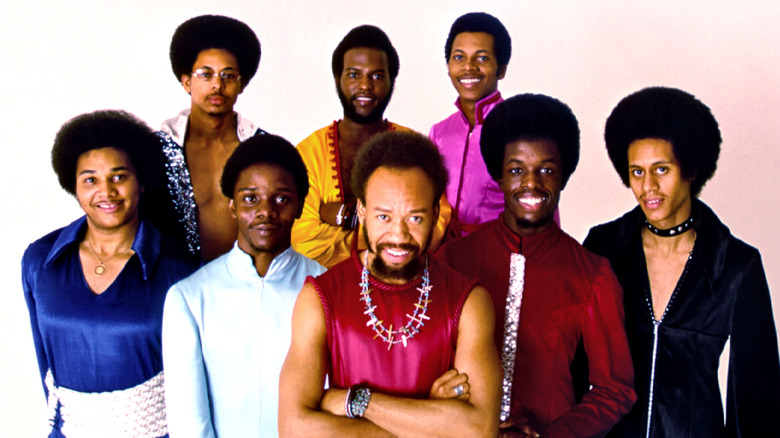 Members of Earth, Wind & Fire against a white and faded pink background