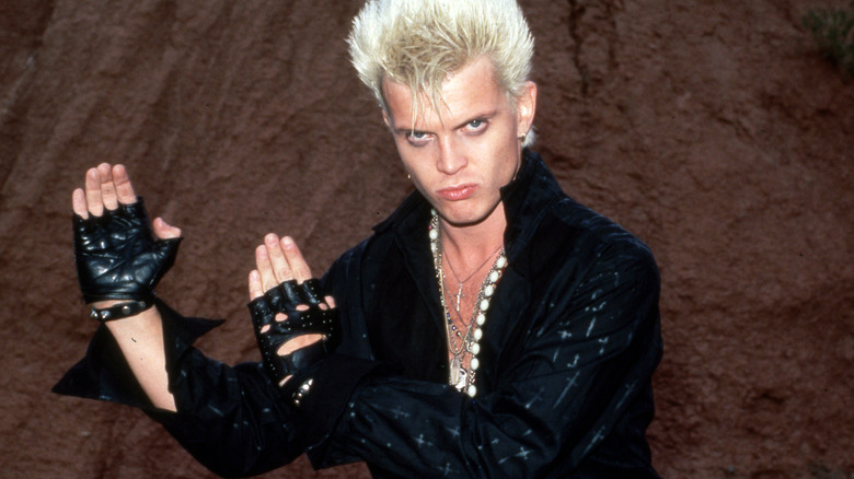 Billy Idol black jacket karate pose brown rock background
