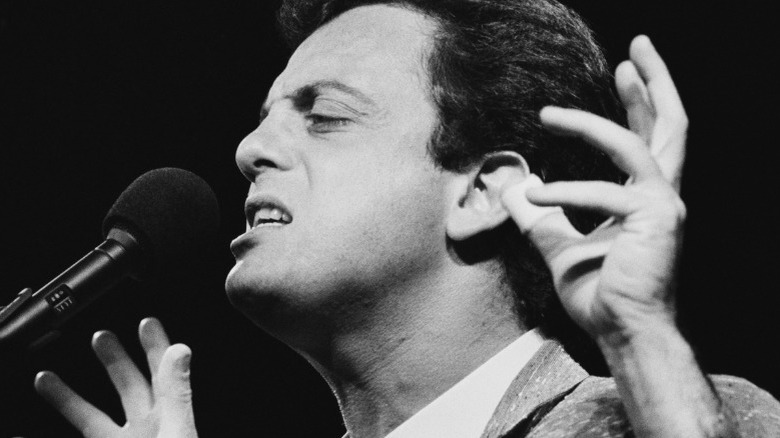 Billy Joel singing with hands up black and white