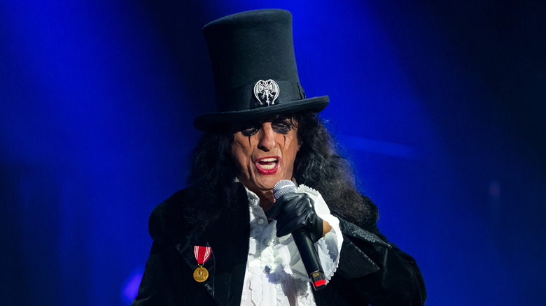 Alice Cooper wearing a top hat and singing on stage in England in 2024