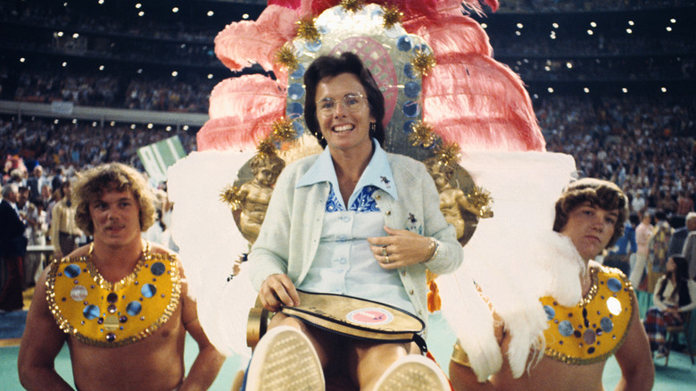 shirtless men carry female tennis star Billie Jean King