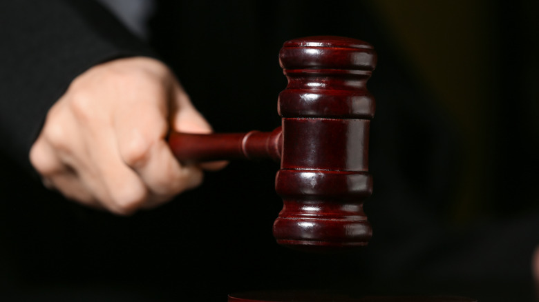 Hand striking gavel on surface, dark background