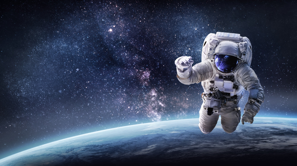 Astronaut floating in space above planet earth