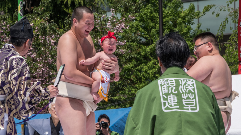 sumo wrestler holding crying child