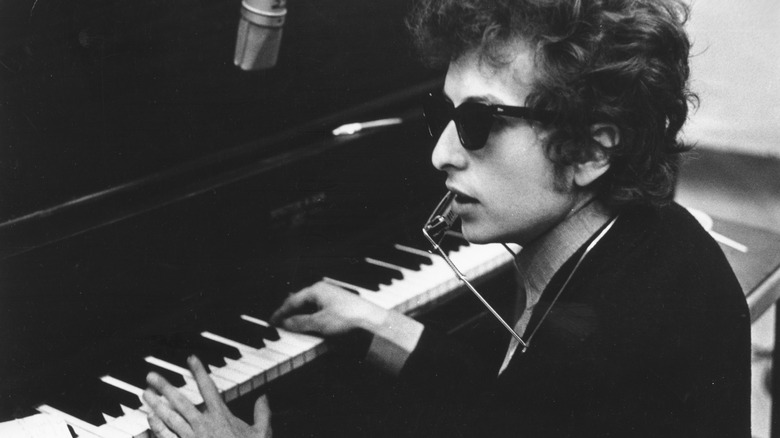 Bob Dylan playing piano while wearing sunglasses