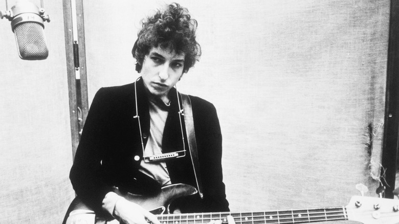 Bob Dylan in studio with harmonica around neck