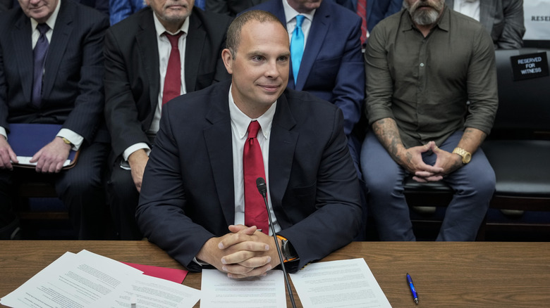 David Grusch hands folded red tie