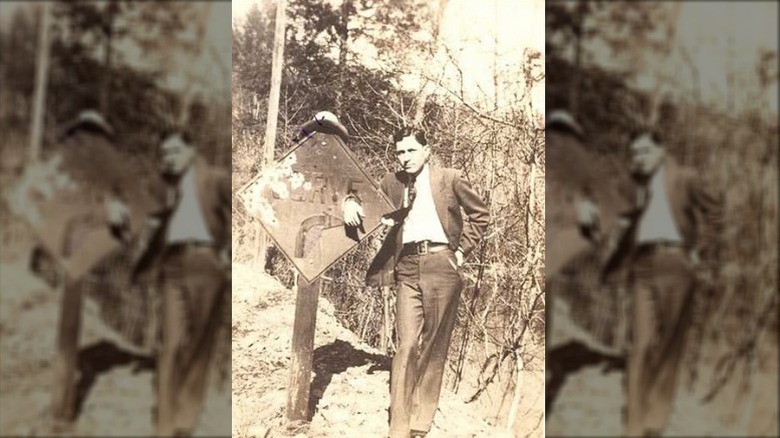 Clyde Barrow arm around road sign