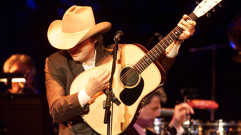 Dwight Yoakam playing the acoustic guitar on stage with a cowboy hat obscuring his face during a 2001 concert
