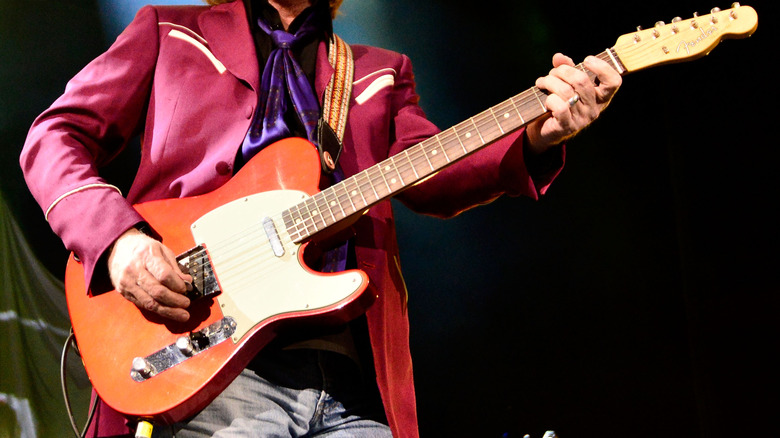 Tom Petty playing guitar on stage