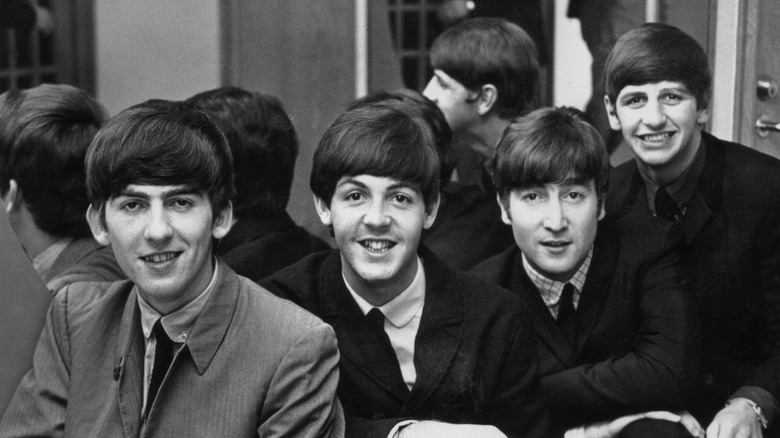 The Beatles in suits posing by mirror
