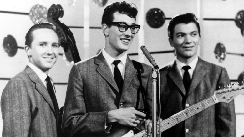 Buddy Holly and the Crickets posing for a photo and smiling on stage.