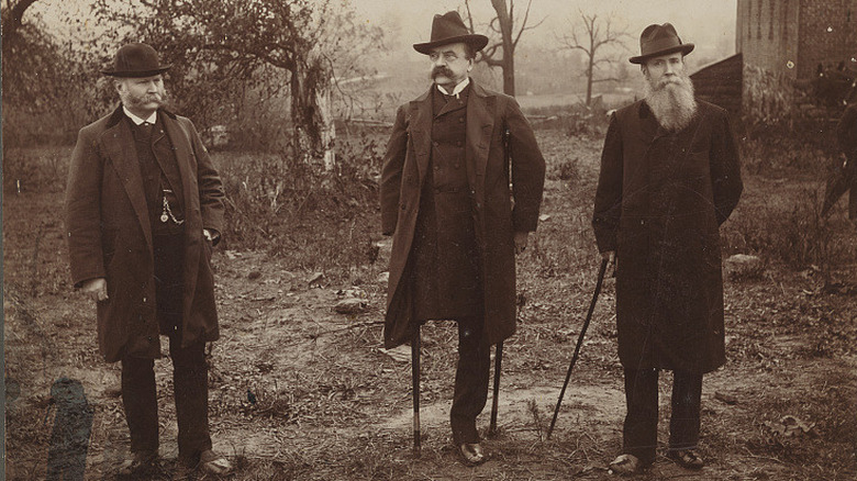 Amputee man stands with two others