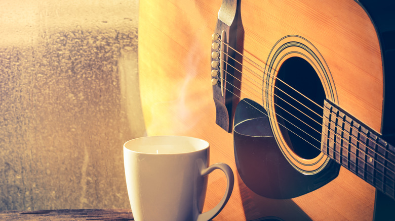 A guitar and a cup of coffee by the window.