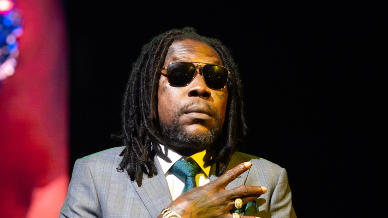 vybz kartel in sunglasses with hand on chest on stage
