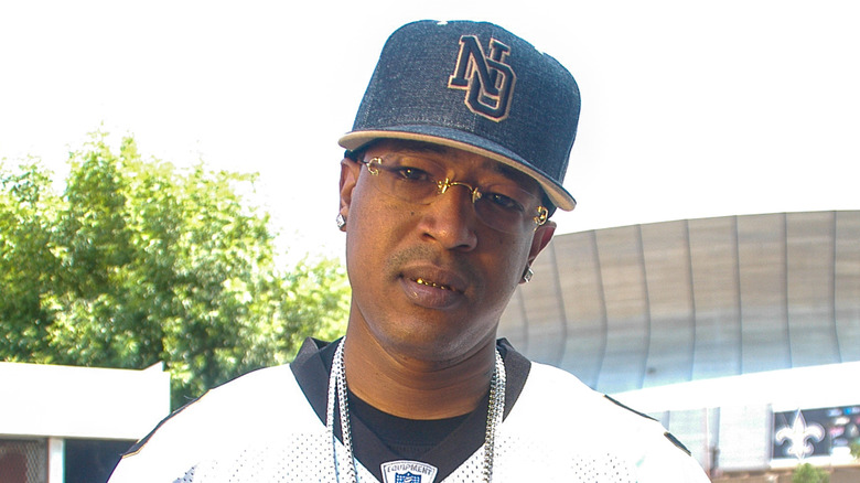 C-Murder wearing blue baseball cap wearing glasses tilting head outdoors