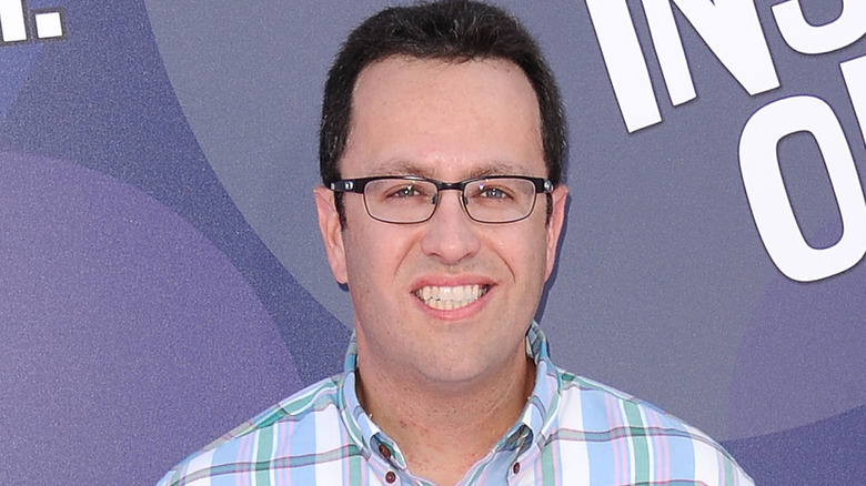 Jared Fogle wearing glasses squinting and grinning at event`
