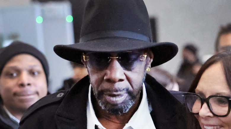 R. Kelly in black suit, wide-brim hat, and sunglasses outside courthouse