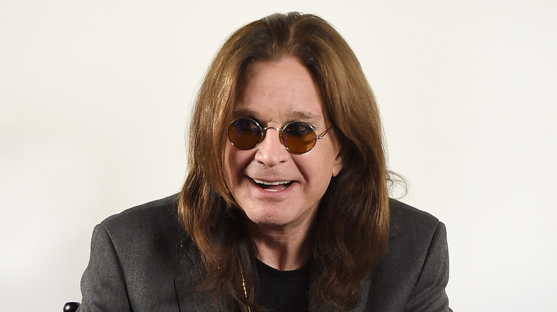 ozzy osbourne smiling wearing suit jacket and round sunglasses