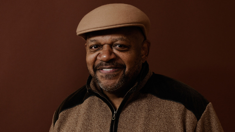 Charles S. Dutton smiling flat cap brown background