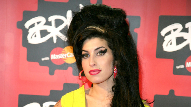 Amy Winehouse with big hair in yellow dress at Brit Awards event