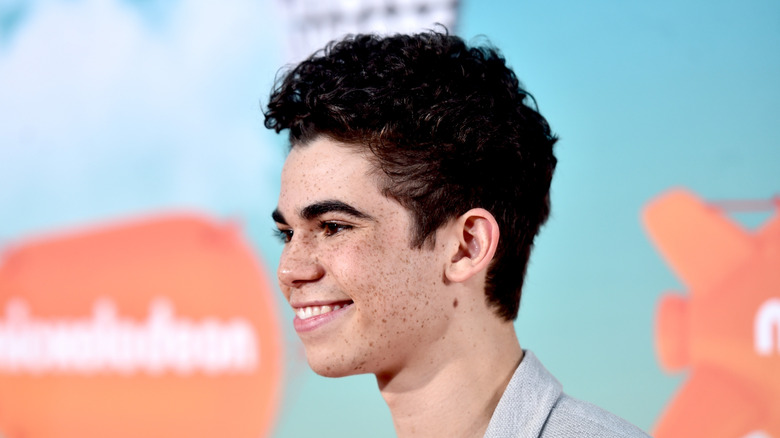 Cameron Boyce smiling in grey suit at Nickelodeon event