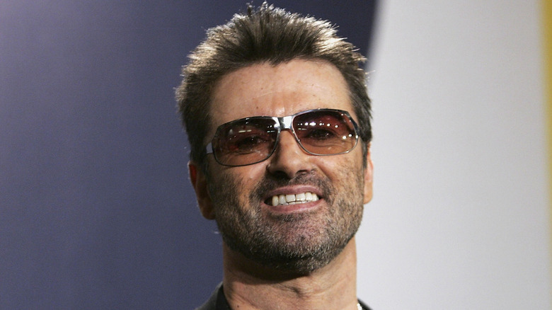 George Michael in sunglasses with stubble smiling