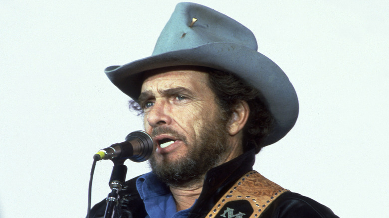 Merle Haggard wearing cowboy hat and singing onstage