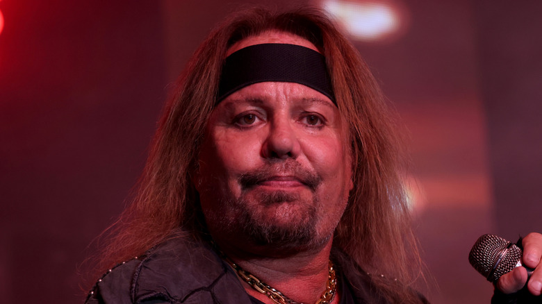 Vince Neil glum on stage holding microphone