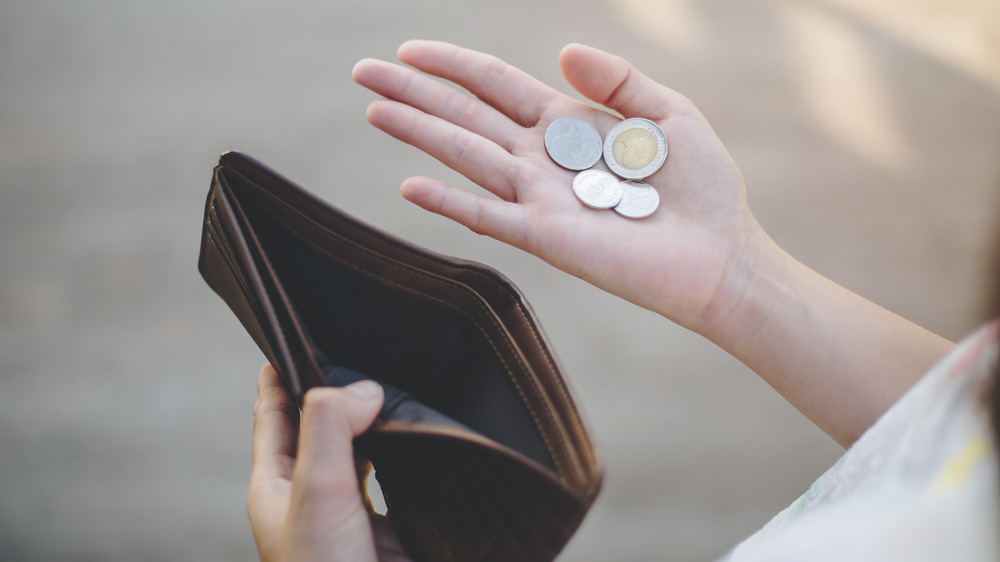 Woman with an empty wallet and a few coins