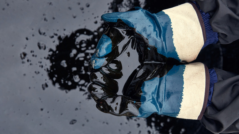 rubber-gloved hands scooping oil  