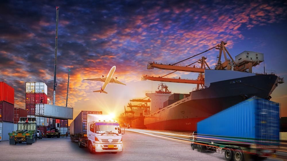 busy port with trucks, ships, and containers, plane overhead