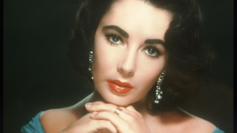 Elizabeth Taylor with head tilted on hands with sparkly earrings
