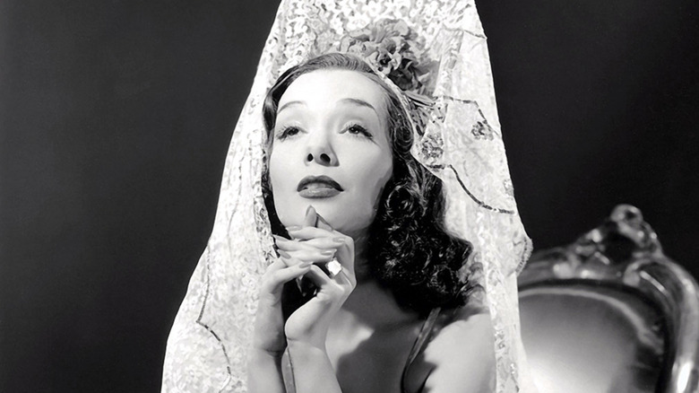 Lupe Velez sat looking up in lace headdress