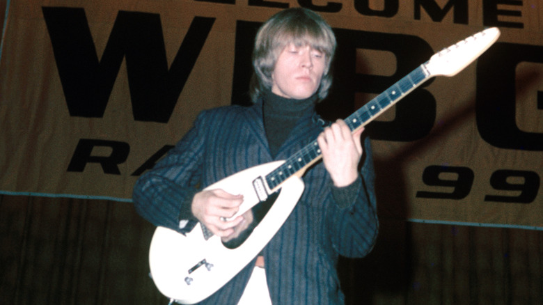 Brian Jones suit strumming white guitar