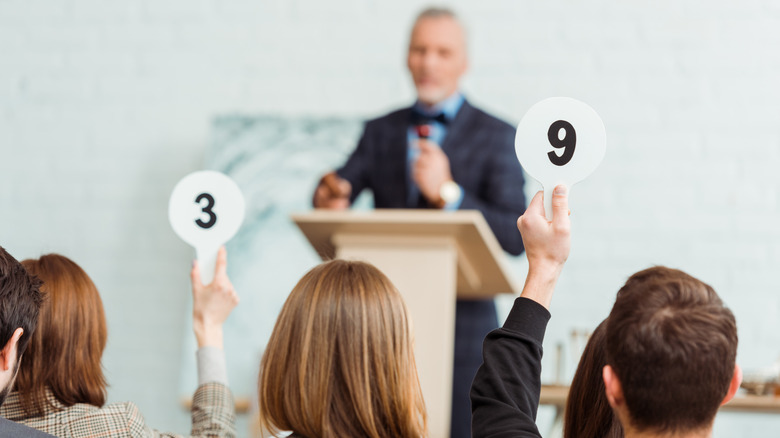 people at an auction holding up numbers