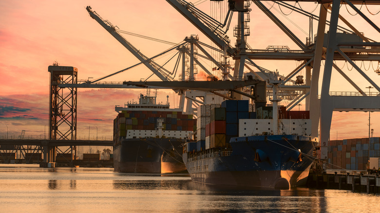 A sunset photo of a cargo ship docked at a loading bay