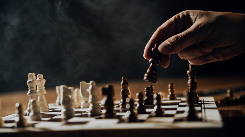 A hand moving a chess piece in the dark