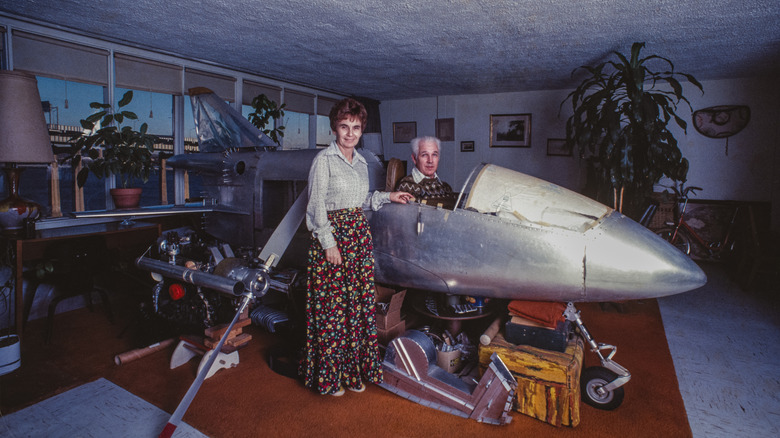 man and woman posing with small homemade airplane indoors