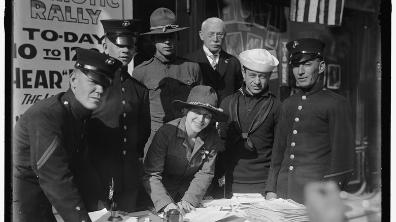 American army recruiter with crowd soldiers and sailors and posters 1917