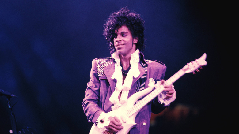 Prince onstage in Purple suit with white guitar